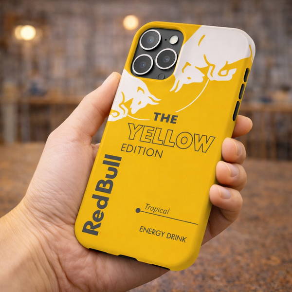 Yellow phone case with Red Bull branding held in a hand against a blurred indoor background